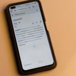 Smartphone displaying the Wikipedia page for ChatGPT on a beige surface.