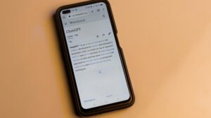 Smartphone displaying the Wikipedia page for ChatGPT on a beige surface.