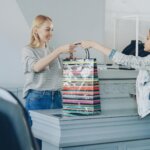 Customer receiving a striped shopping bag from a cashier at a clothing store counter