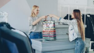 Customer receiving a striped shopping bag from a cashier at a clothing store counter