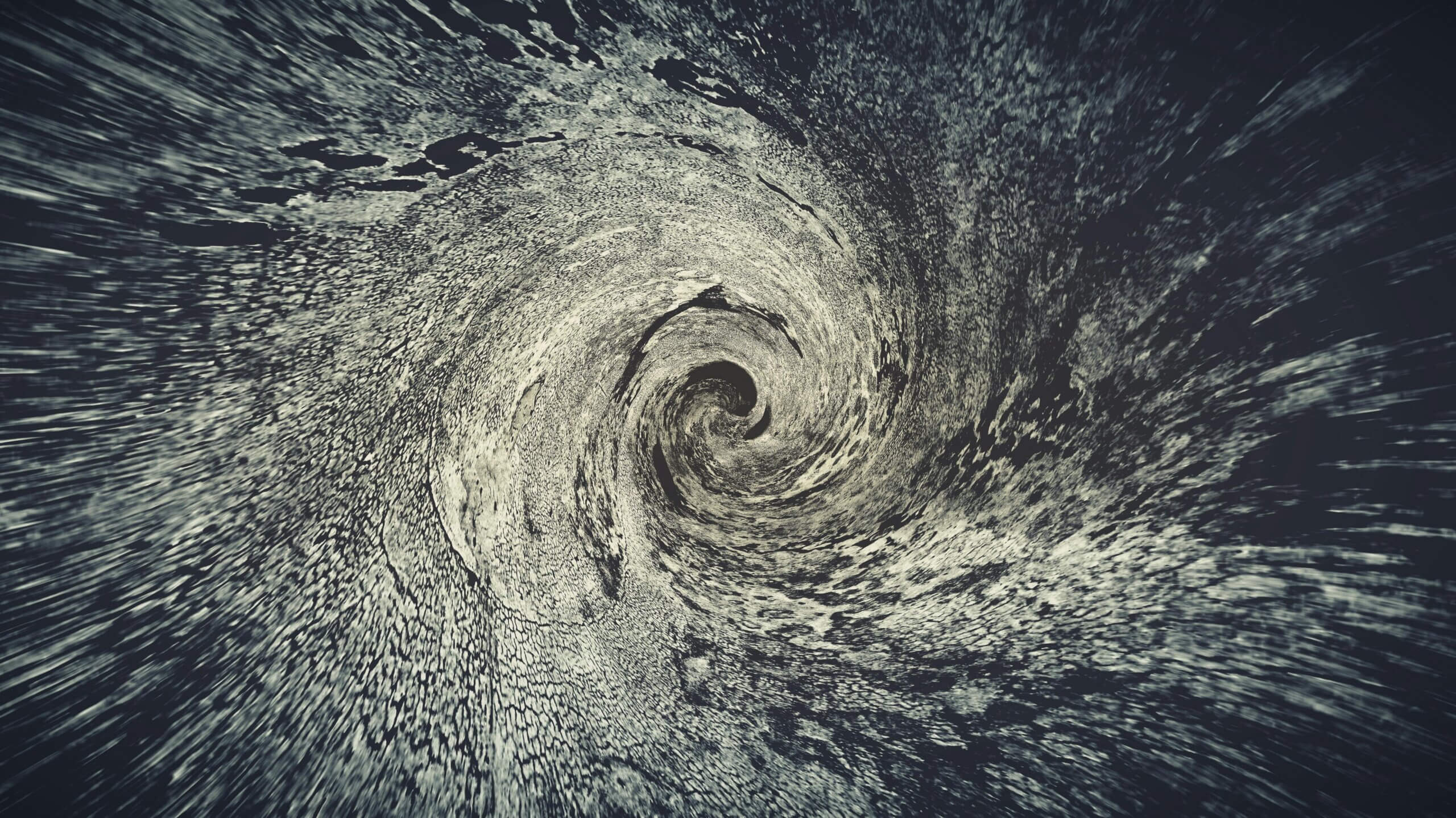 abstract black and white swirling vortex pattern with textured, grainy appearance