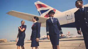 British Airways pilots and flight attendants walking on the tarmac near a British Airways airplane tailfin