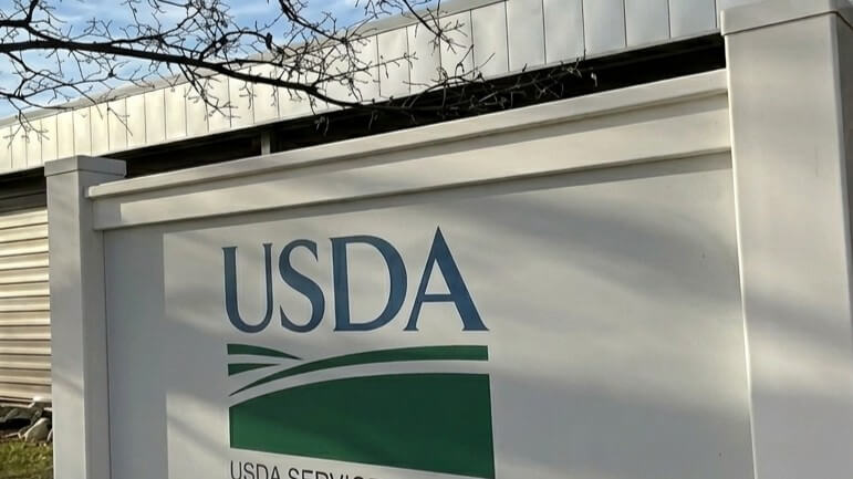 USDA sign with green and blue logo outside a building under a clear sky