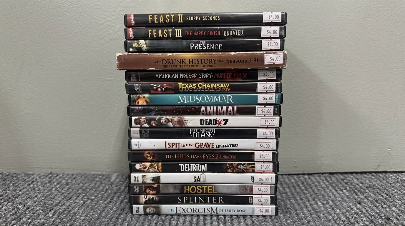 Stack of horror and thriller DVDs including Feast II, Midsommar, Texas Chainsaw, Saw, and The Exorcism of Emily Rose with $4 price tags.