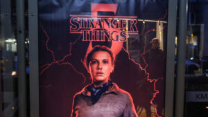 Stranger Things Season 5 poster featuring Eleven with a nosebleed and lightning effects at a bus stop at night
