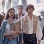 Anne Hathaway and James Frain in medieval costumes walking in a stone archway scene from The Princess Diaries 2