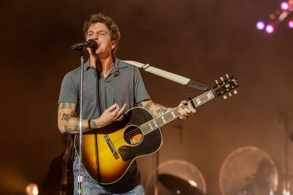 John Mayer singing and playing acoustic guitar on stage during a concert