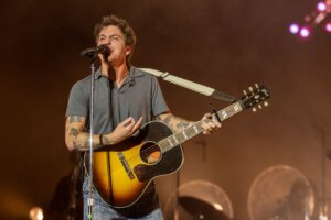 John Mayer singing and playing acoustic guitar on stage during a concert