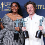 Two actors holding Screen Actors Guild Awards trophies at the SAG Awards event with Netflix branding in the background