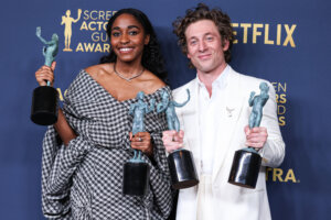 Two actors holding Screen Actors Guild Awards trophies at the SAG Awards event with Netflix branding in the background