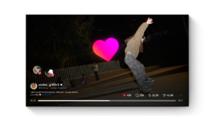 Skateboarder stellas_gr00v3 performing a kickflip at night in a skatepark with spectators in the background.