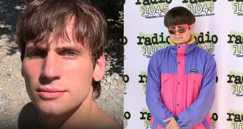 Close-up of a young man with brown hair outdoors next to a man wearing a purple and pink Montbell jacket and red sunglasses at Radio 104.5 event
