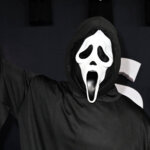 Person wearing Ghostface costume from Scream holding a knife with multiple Ghostface masks in the background