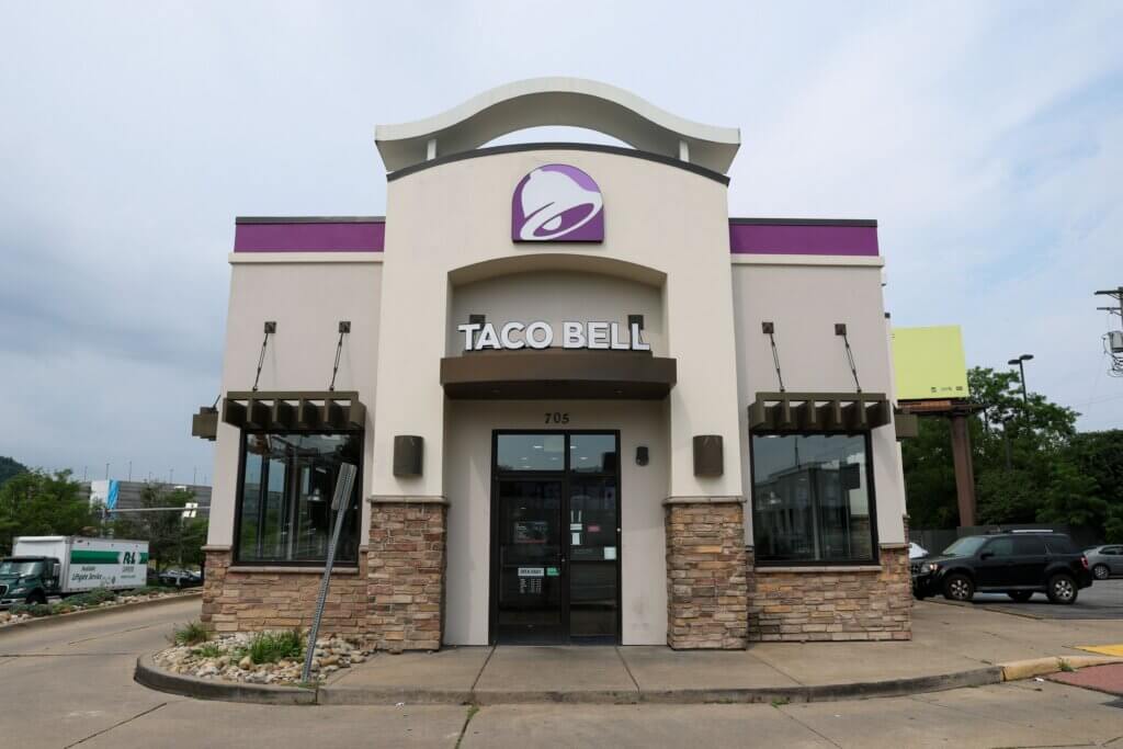 Taco Bell restaurant exterior with purple logo and stone accents under cloudy sky