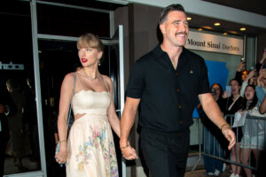 Taylor Swift and Travis Kelce holding hands outside Mount Sinai Doctors with fans taking photos nearby