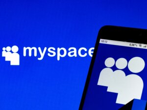 Myspace logo displayed on a blue background and partially on a smartphone screen.