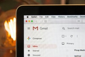 MacBook screen showing Gmail inbox open in Safari browser with Compose button visible