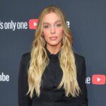 Blonde woman in black suit posing on red carpet at YouTube event with "There's only one YouTube" backdrop