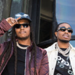 Rapper Takeoff wearing a purple jacket and cap next to rapper Quavo in a white jacket and sunglasses outdoors