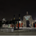 Los Angeles Memorial Coliseum entrance at night with illuminated signage and statues.