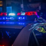 Police car roof with flashing red and blue emergency lights at night in an urban setting