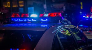 Police car roof with flashing red and blue emergency lights at night in an urban setting
